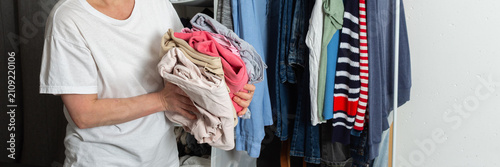 Obraz na płótnie A 52-year-old woman stands by a bed and sorts clean laundry