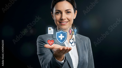 Professional woman holding digital icons for health insurance and medical protection coverage in palm with smiling businesswoman presenting digital symbols healthcare insurance