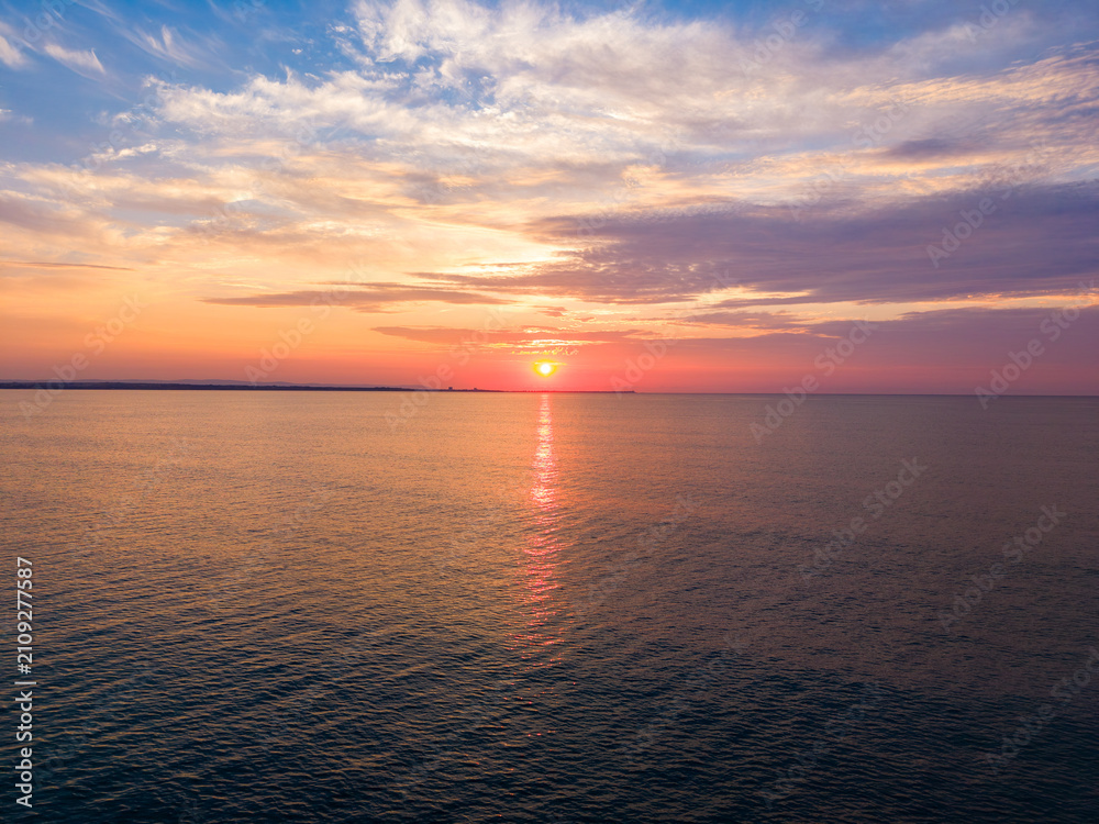 Obraz premium Sunset over water with horizon and clouds in evening light