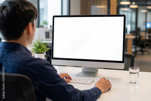 Professional Using Desktop Computer with Blank White Screen Mockup in Modern Office Workspace for Business Technology and Copy Space
