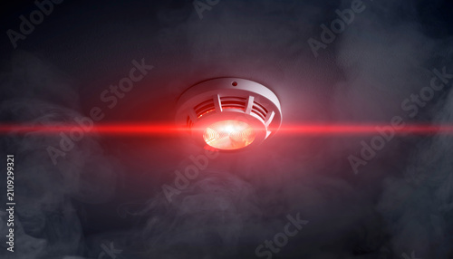 A smoke detector emitting a red alert signal in the dark.