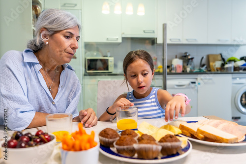 Billede på lærred Grandmother and granddaughter sharing a healthy breakfast at home
