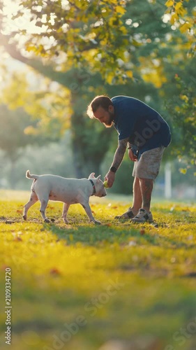 Tattooed man playing with his bull terrier dog in the park