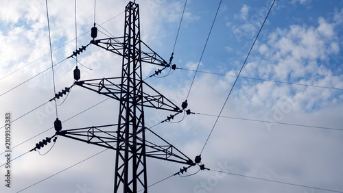 Картината върху платно High voltage electricity pylon silhouetted against a cloudy blue sky