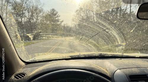 POV of a dirty car windshield heavily covered in a thick layer of yellow spring pollen