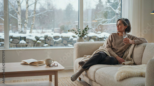 Midlife Woman Drinking Ice Water for Menopause Hot Flash Relief While Relaxing at Home in Winter