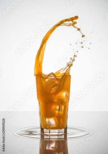 Fresh orange juice splashing into a tall glass filled with ice cubes, creating vibrant droplets and ripples on a clean, reflective surface, wet, close-up, droplets