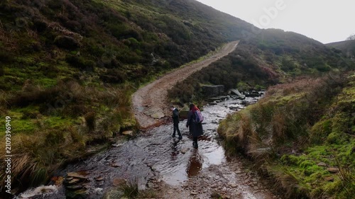 Mother and son walking on the Yorkshire Moorlands in the English countryside. Bleak barren moors or pennines. Calm lake with heather covered hills.