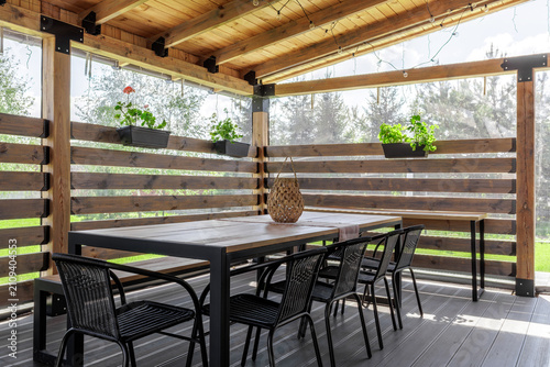 Covered Wooden Terrace with Dining Set and Plants