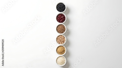 Assorted dry beans and grains in small bowls arranged in a vertical line