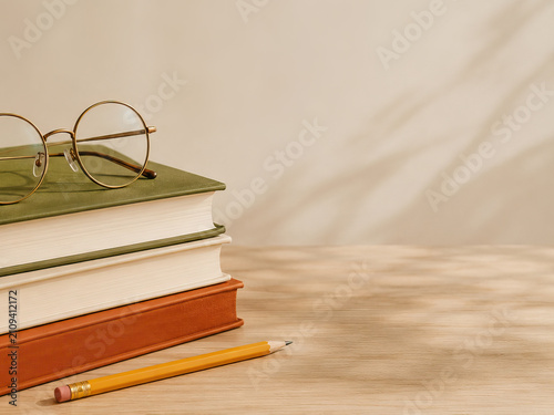 A minimalist image depicting a study scene with stacked books, glasses, and a pencil, conveying a sense of tranquility and focus on learning.