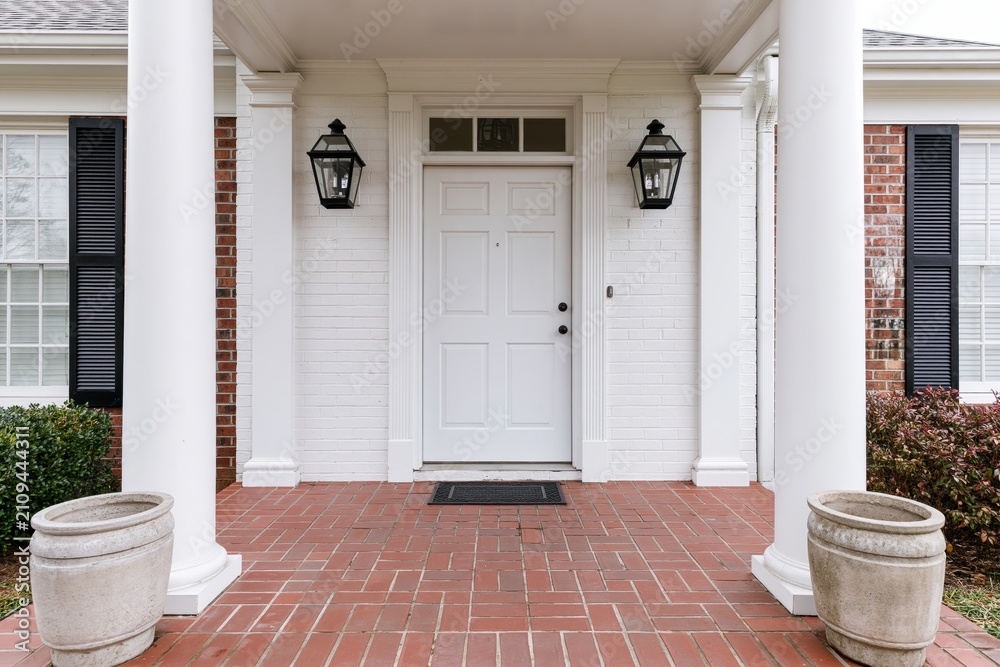 Obraz premium The White Front Door on a Brick Porch with Lanterns