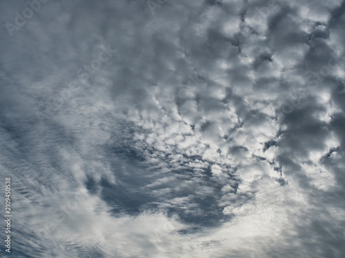 Foto Altocumulus clouds white and gray  with a patchy, puffy or wavy structure resembling ripples occurring in the middle level of the atmosphere