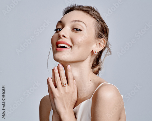 Fotografie Elegant Woman Displaying Jewelry with Joyful Expression and Soft Natural Makeup