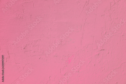 Pink stucco wall with scratches and rough textured surface plaster. Minimalist colorful background featuring weathered concrete structure and abstract pastel details.