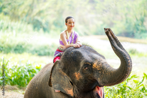 Fotografie A beautiful rural Thai woman in the Thai northern traditional dress riding outdo