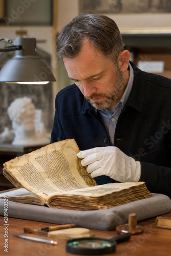 Male Archivist Turning Pages Illuminated Medieval Manuscript White Gloves Museum Study Room