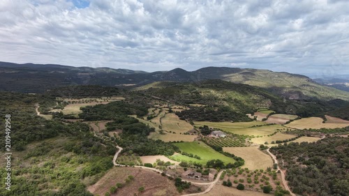 Flying over mountainous Pyrenees landscape with farmland, pastures, olive and almond groves. 