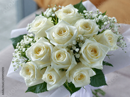 Beautiful bouquet of fresh white roses and babys breath flowers wrapped in paper
