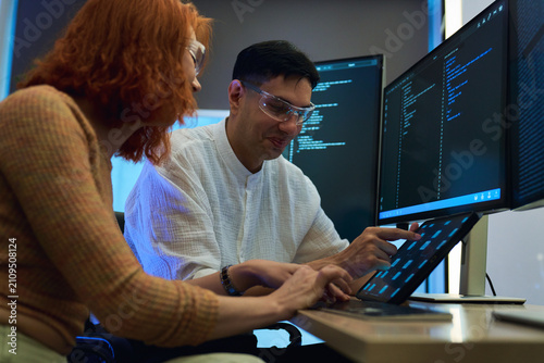 A professional male and female software developer working together on a complex programming project