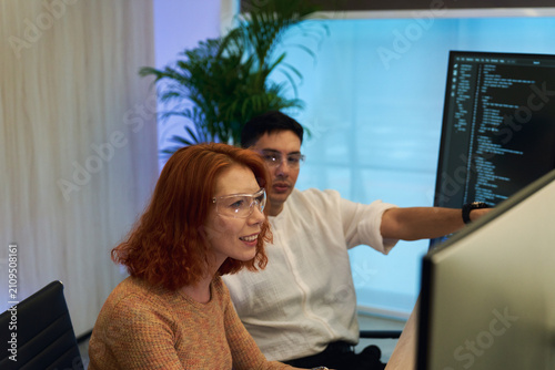 Two Diverse Software Engineers Collaborating on Code in Modern Tech Office