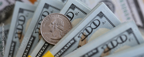 US coin lies among ten thousand dollars packs in stack on big amount of hundred dollar bills