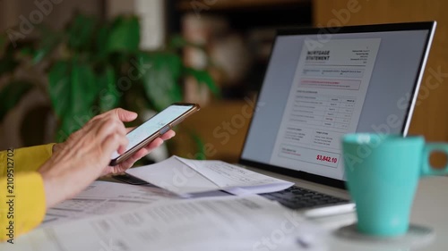 Woman calculating utility bills and household expenses on smartphone calculator.
