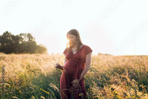 Pregnant woman enjoying nature during sunset golden hour
