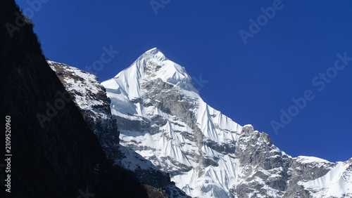 Neelkanth Parvat, a majestic snow-capped peak towering over the rugged terrain of Badrinath in the Himalayas under clear blue skies