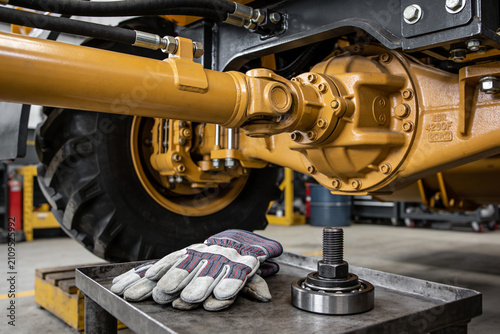 Obraz na płótnie Heavy machinery drivetrain components and work gloves on a metal tray