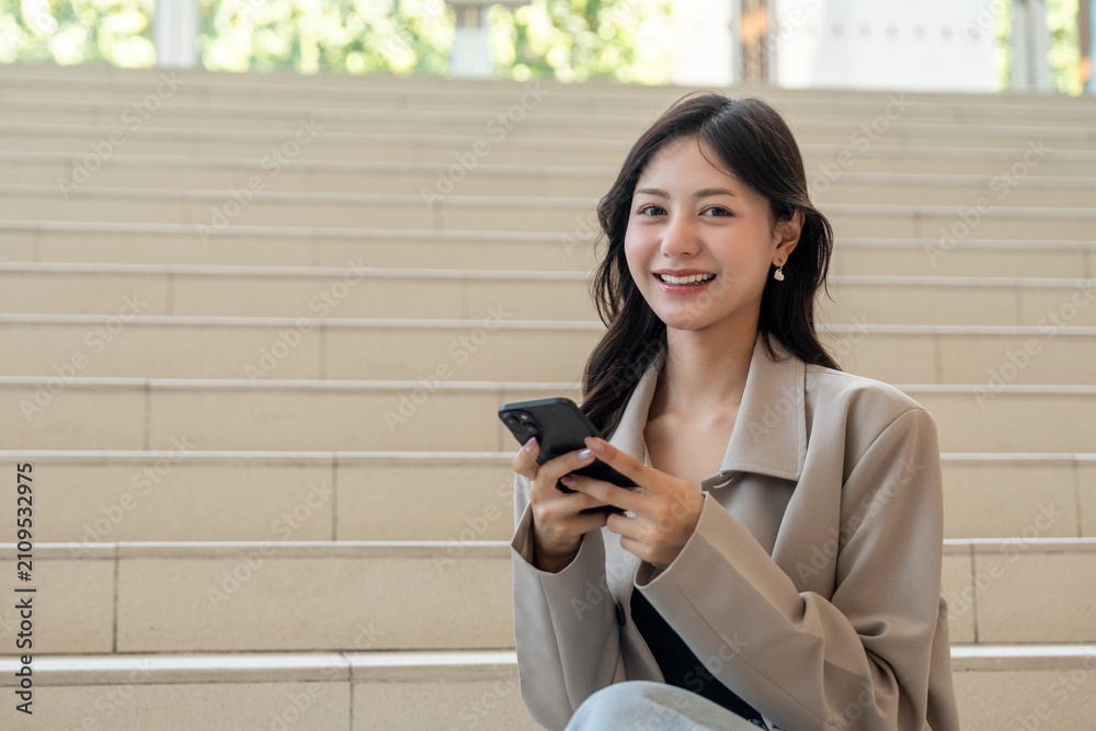 Fototapeta premium Beautiful business woman using mobile phone work in business buildings. Smart female using cell phone chatting for business communication talking. Business lifestyle concept.