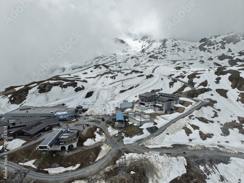Kitzsteinhorn, Austria - June 09 2026: Cinematic 4K drone footage tracking a snowmobile as it rides across the snowy ski slopes of Kitzsteinhorn Glacier in Kaprun, Austria. Spectacular aerial views sh