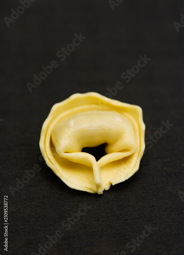 one single tortellino on black fabric