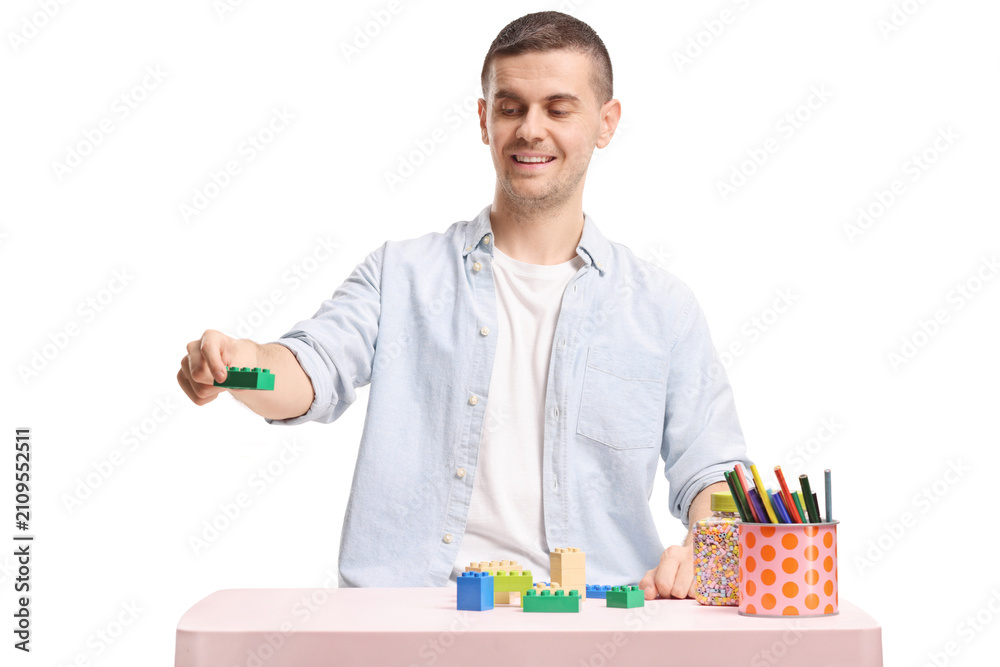 Fototapeta premium Young man playing with building blocks at a table