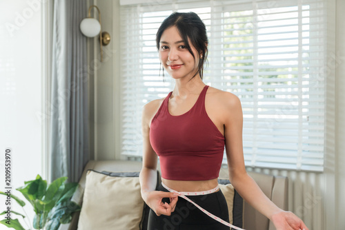 Cuadro en lienzo Asian Woman measuring her waistline with measure tape