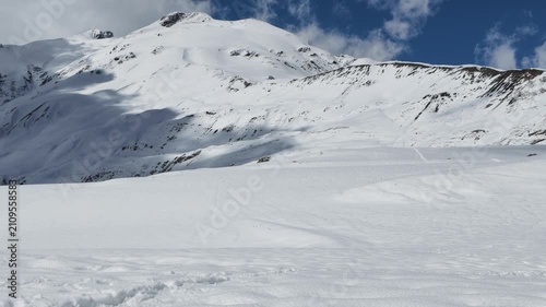 Snowy Koruldi ridge landscape in Svaneti Georgia, high altitude mountain peak under blue sky with clouds