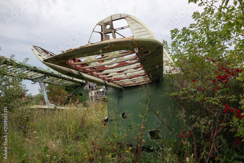 Abandoned aircrafts in overgrown airfield with tall grass under cloudy skies