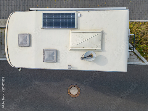 Foto Top down aerial view of a motorhome roof equipped with a solar panel, roof vents, and satellite dish parked on an asphalt street