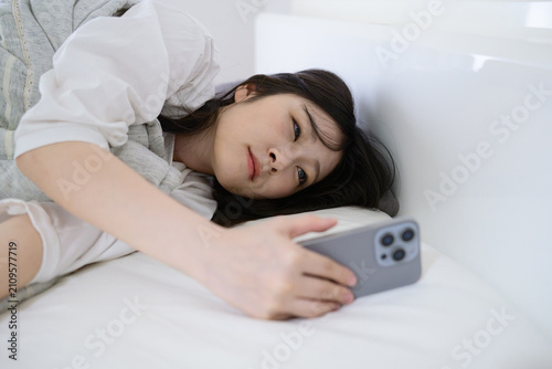 スマホのアラームを止める寝起きの20代日本人女性