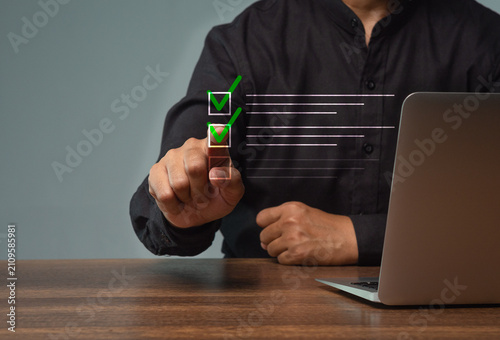 Foto Person completing digital checklist beside laptop*