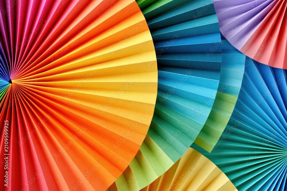 Fototapeta premium Vibrant rainbow fan folds made of paper create a colorful abstract background with a radial pattern.
