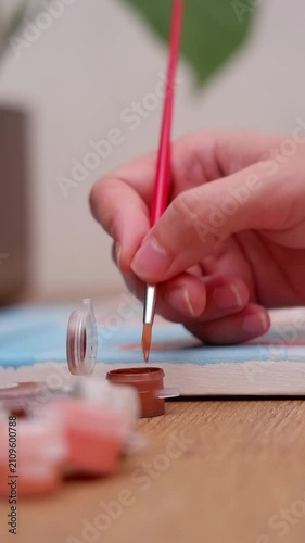 Close up of an artist's hand painting a picture with a brush, creating art as a relaxing hobby