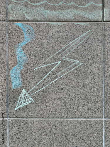 Chalk drawing of a lightning bolt symbol on grey stone pavement.