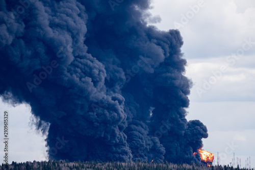 Canvastavla Towering plume of dense black smoke rising from a large oil tank engulfed in fla