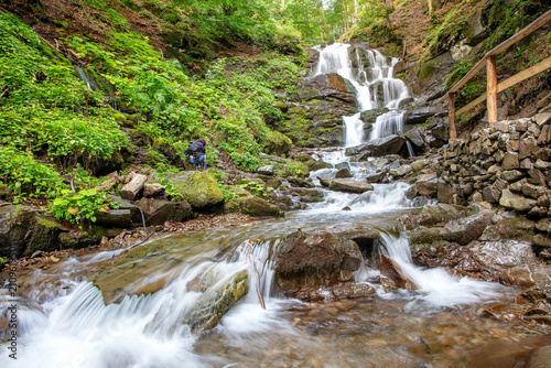 Water flows down rocks in a forest setting near a small waterfall during daytime