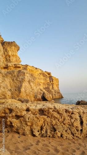 Quadro su tela Weathered limestone cliffs with natural caves under clear blue sky on Mediterran