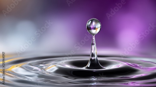 A high-speed macro capture of a single water drop hitting a liquid surface, creating a perfect sphere and ripple effect with vibrant purple and violet neon lighting.