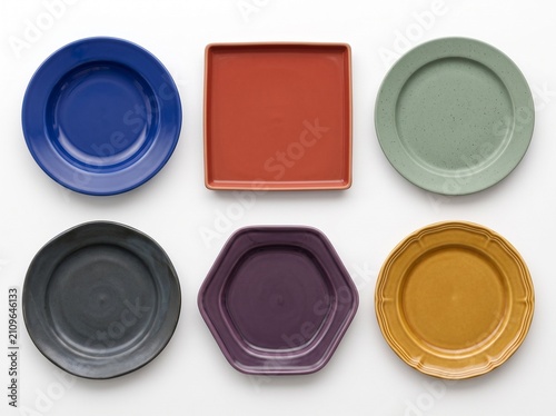 Collection of six diverse ceramic plates in various shapes and colors arranged on a white background