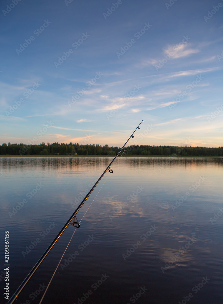 Fototapeta premium Fishing on a lake. Rod against sunset. 