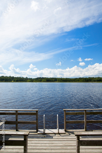Small pier on a lake shore. Finnish relaxation moment during the holidays. Sunny and calm weather. Place for swimming and fishing.